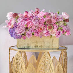 Pink and lavender floral arrangement in a gold rectangular box
