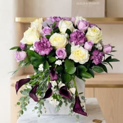 Bouquet of cream and lavender roses with purple calla lilies in a white box
