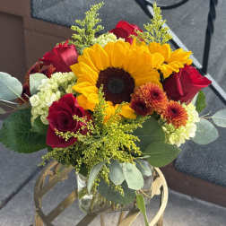 Bouquet with a sunflower, red roses, and orange mums in a glass vase