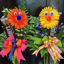 Two novelty flower arrangements with smiling faces in glass vases