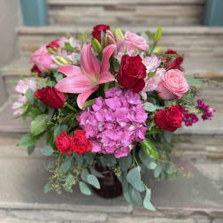 Pink lilies and red roses arranged with hydrangea in a vase