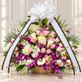Large funeral spray with pink roses, white lilies, and purple orchids in a basket