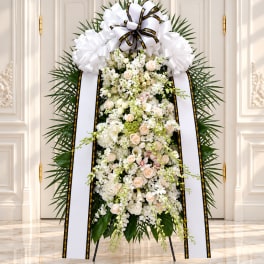 White funeral standing spray with ribbons on an easel