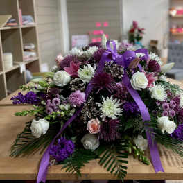 Purple and white floral spray with ribbon on a table