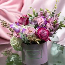 Mixed pink and purple flowers arranged in a lavender hatbox