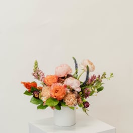 Colorful mixed flower arrangement in a white cylindrical vase