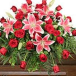 Red roses and pink lilies arranged on a wooden casket