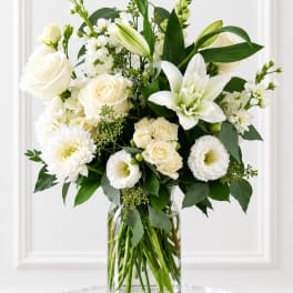 White roses and lilies arranged in a clear glass vase