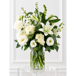 White roses and lilies arranged in a clear glass vase