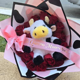 Bouquet of red roses with a plush cow and pink ribbon