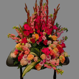 Large floral arrangement with pink and peach roses and tall pink spikes