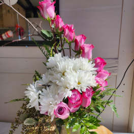 Pink roses and white daisies arranged in a glass vase