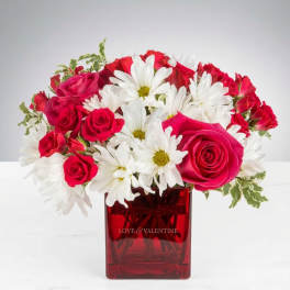 Red roses and white daisies in a red glass vase