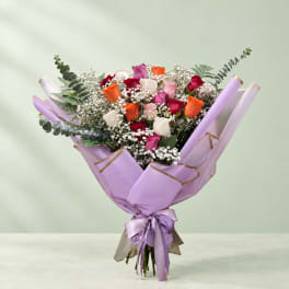 Bouquet of multicolored roses wrapped in lavender paper with a ribbon