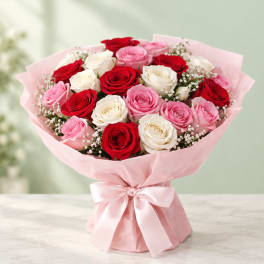 Bouquet of red, pink, and white roses wrapped in pink paper with a ribbon
