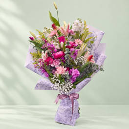 Pink and purple mixed bouquet wrapped in lavender paper with a satin ribbon