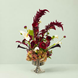Tall floral arrangement with burgundy and white blooms in a silver pedestal vase