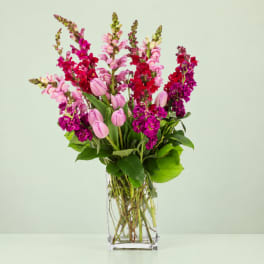Tall bouquet of pink and magenta flowers in a clear glass vase