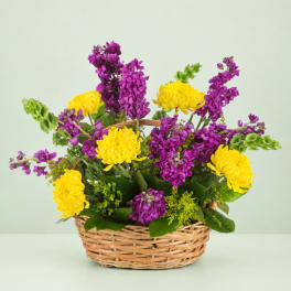 Basket arrangement of yellow chrysanthemums and purple flowers