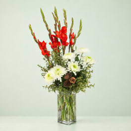 Red gladiolus and white chrysanthemums in a clear glass vase