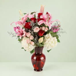 Pink lilies and red roses in a red glass vase