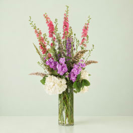 Tall mixed bouquet in a clear glass vase with pink, purple, and white blooms