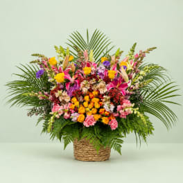 Colorful mixed flower arrangement in a woven basket with palm fronds