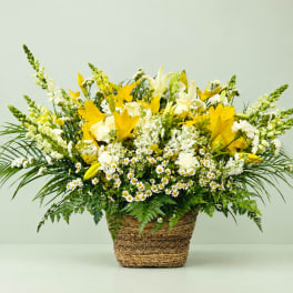 Yellow and white mixed flower arrangement in a woven basket