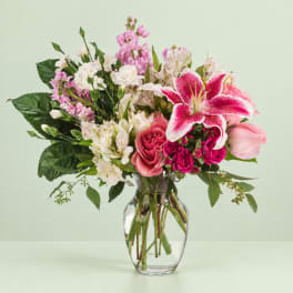 Mixed pink and white flowers arranged in a clear glass vase