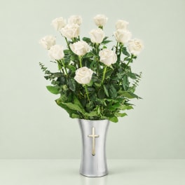 White roses in a silver vase with a cross emblem