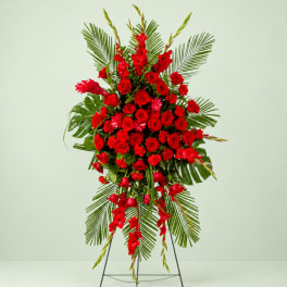 Tall red floral standing spray with palm fronds on a metal easel