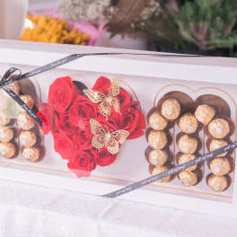 Gift box with red roses and chocolate truffles arranged in heart shapes