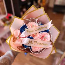 Pink and blue rose bouquet with gold-edged wrapping and ribbons