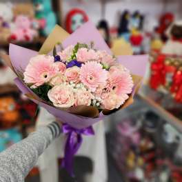 Bouquet of pink gerbera daisies and roses wrapped in purple paper