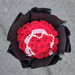 Bouquet of red roses wrapped in black paper with a white ribbon
