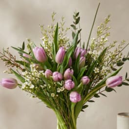 Pink tulips arranged with white filler flowers in a loose bouquet