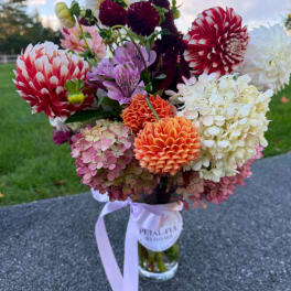 Mixed bouquet of dahlias and hydrangeas in a glass vase with a ribbon