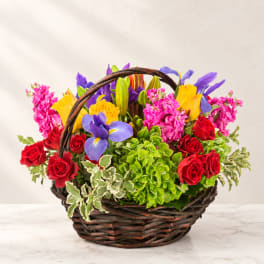 Colorful mixed flower basket with roses, lilies, and iris in a wicker basket