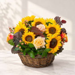 Basket arrangement of sunflowers and peach roses