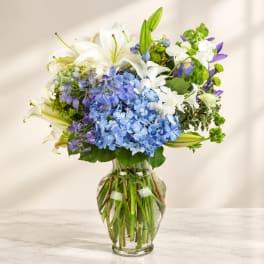 Blue and white flowers arranged in a clear glass vase
