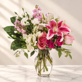 Mixed pink and white flowers arranged in a clear glass vase