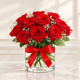 Red roses in a clear glass vase with a red ribbon bow