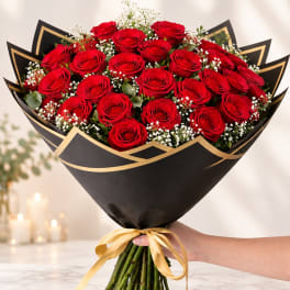 Bouquet of red roses wrapped in black paper with a gold ribbon