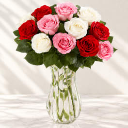 Bouquet of red, pink, and white roses in a clear glass vase