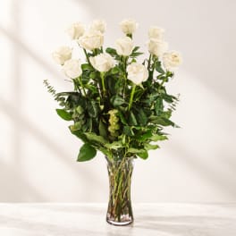 White roses arranged in a tall clear glass vase