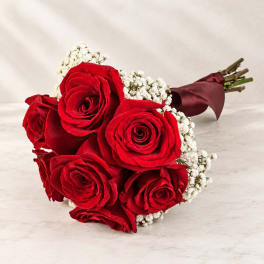 Bouquet of red roses with white baby's breath wrapped in burgundy paper