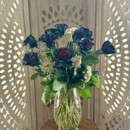 Dark roses in a clear glass vase on a wooden table