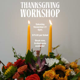 Floral arrangement with two lit orange candles and mixed autumn flowers