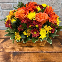 Basket arrangement of orange roses, gerbera daisies, and yellow chrysanthemums