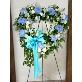 Heart-shaped floral wreath with blue and white flowers on a stand